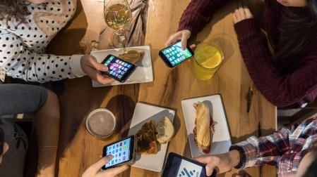 Un grupo de amigas consulta su móvil paga pagar la cuenta en un bar de Pamplona