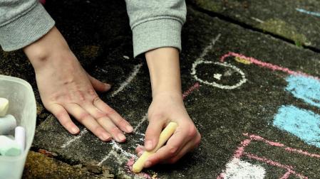 Un niño pintando en el suelo con unas tizas