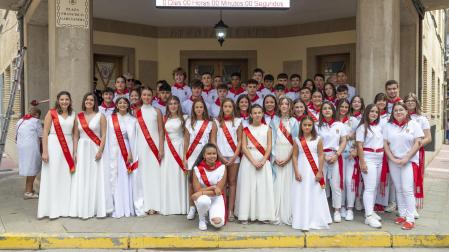 Foto de familia a los pies de la casa consistorial entre quintos, damas y la reina de las fiestas.
