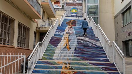Las escaleras decoradas por un mural y, al fondo, el ascensor que salva su desnivel