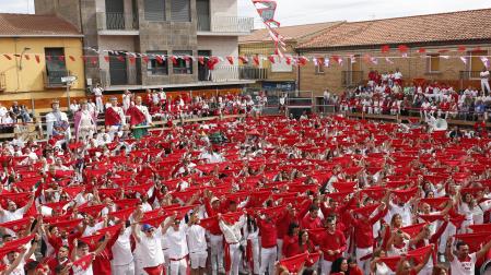 Los asistentes al lanzamiento del cohete de las fiestas de San Miguel de Cortes alzan sus pañuelos tiñendo de rojo la plaza del Ayuntamiento.