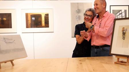 La fotógrafa Mar Mateo y el pintor José Ignacio Agorreta se abrazan en La Fábrica de Gomas. A su alrededor, algunos de los cuadros y las fotos que exponen