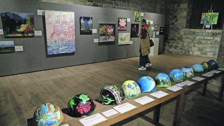 En primer término, los cascos pintados por niños, en la exposición Artistas de la guerra.