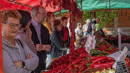 Varias personas esperan en un puesto de pimientos de Puente la Reina a ser atendidas mientras  observan y eligen el tipo de pimiento que van a adquirir