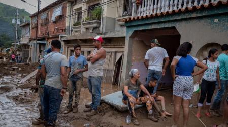 Los vecinos descansan tras trabajar para quitar toda la tierra que entró a sus viviendas dañadas por las lluvias