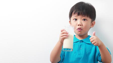 Un niño desayuna un vaso de leche