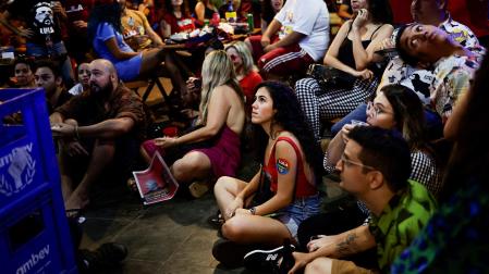 Varias personas observan el debate televisado entre Lula Y Bolsonaro en un bar de Brazilia