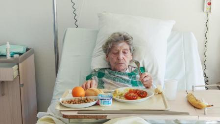 Una persona mayor come en la cama de un hospital
