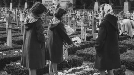 Tres niñas rodean una tumba en el cementerio de Pamplona en la festividad de Todos los Santos de 1959