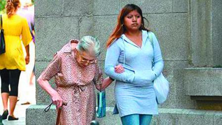 Una joven latina acompaña del brazo a una señora mayor por la calle