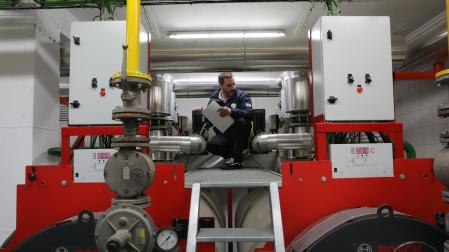 Un técnico revisa la sala de caldera de una comunidad con calefacción central.