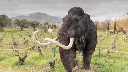 Recreación de un mamut en primer plano y dinosaurios al fondo, en el parque de dinosaurios de Atenas (Grecia).