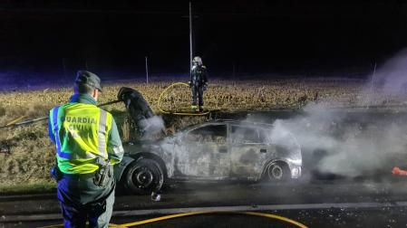 Un agente de la Guardia Civil, junto al vehículo quemado en la NA132