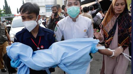 Rescatadores y una madre trasladan el cuerpo de un niño, víctima del terremoto
