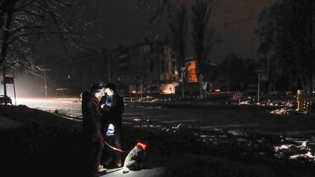 Dos personas se alumbran con un teléfono móvil en una calle oscura de Kiev, donde la mitad de la ciudad sigue sin electricidad y dos tercios de los hogares no tienen calefacción