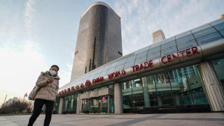 Una mujer con mascarilla camina por el distrito financiero de Beijing