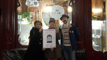 Ventura Ruiz (Zerokotan), Maite Mardo (LaMai) y el poeta Yoel Saldaña, mostrando el cartel de la iniciativa Poesía de escaparate