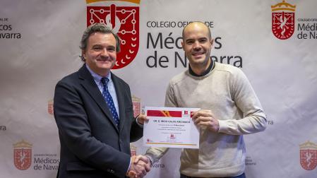 El cirujano Íñigo Calvo (derecha) recibe la beca de la mano del presidente del Colegio de Médicos de Navarra, Rafael Teijeira.