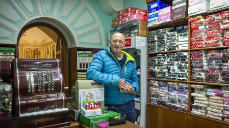 Paco Roda posa tras el mostrador de Mercería Ferrán, en la calle Mayor, un negocio que este 2022 ha cumplido un siglo y que tiene a Paqui Etayo al frente desde hace 51 años