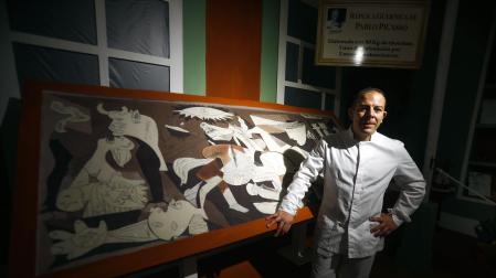 Jorge Garrido posa junto al cuadro del Guernica elaborado con chocolate en el obrador Galleros Artesanos de Rute (Córdoba)