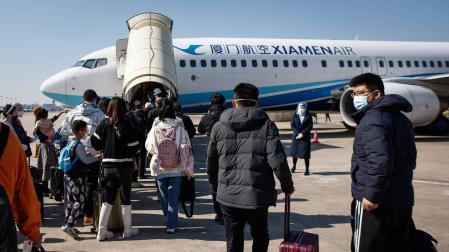 Pasajeros se dirigen por las pistas al avión que les llevará desde del aeropuerto de Xiamen a Pekín