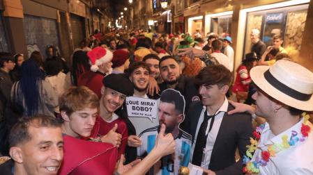 Mikel Aceldegui, con camisa y corbata, junto con su cartel de Messi en la calle San Nicolás, uno de los lugares más concurrido de la noche
