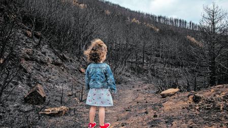 Emma Cerdán, de 3 años, observa el monte calcinado por las llamas en el término de Beragu en una imagen tomada el 25 de junio
