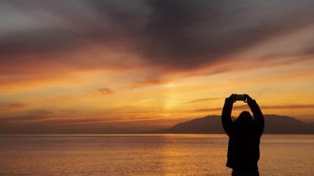 Una persona toma una foto del atardecer en una playa el último día del año