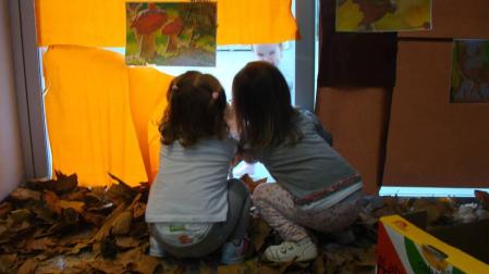 Dos infantes miran a través de la ventana de la Escuela Infantil Hello Egunsenti