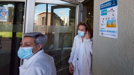 Dos profesionales junto a la puerta de acceso del Hospital Universitario de Navarra donde había un cartel informativo sobre la huelga