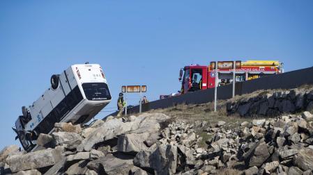 El microbús, volcado sobre las rocas tras el accidente en cabo Silleiro (Baiona)