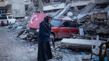 Una anciana camina entre los escombros de un edificio derribado por el terremoto en la localidad turca de Hatay.