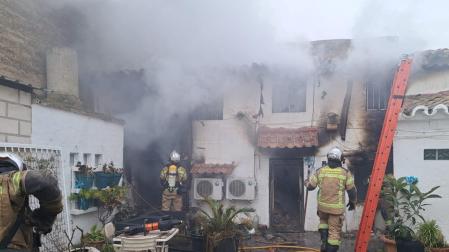 Efectivos de bomberos trabajan en la vivienda incendiada