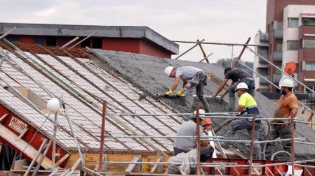 Varios empleados de la construcción trabajan en el tejado de un edificio