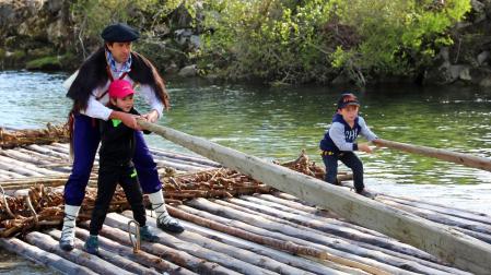 Un hombre y dos niños navegan el Esca en Burgui el día de la almadía