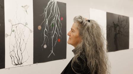 Ángela Moreno contempla un tríptico en blanco y negro del proyecto Cuando los sueños miran a los ojos instalado en El Sario