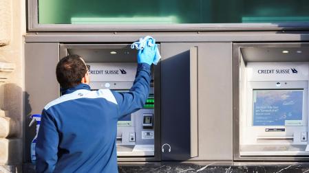 Un operario limpia un cajero automático de una entidad de Credit Suisse este lunes 20 de marzo en Zurich.