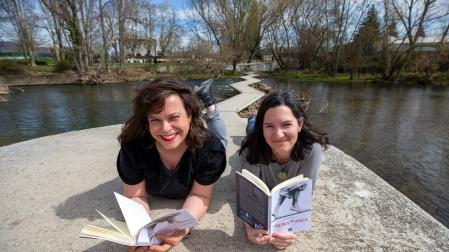 La actriz Tefi de Paz (izq.) y la editora Iruña Iriarte, posando con el libro en las Pasarelas del Arga, bautizadas en 2021 como ‘Pasarelas de Mademoiselle Agustini’