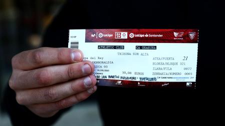 Uno de los aficionados sujeta la entrada para el Athletic-Osasuna de la vuelta de la semifinal de la Copa del Rey.