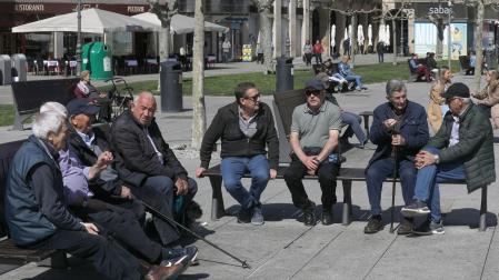 Dos grupos de hombres charlan al sol en la Plaza del Castillo de Pamplona