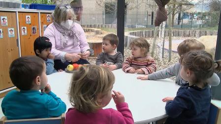 Una educadora prepara fruta a un grupo de niños en una escuela infantil de Pamplona
