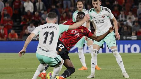 Kike Barja trata de impedir que Baba se lleve el balón ante la mirada de Aimar Oroz