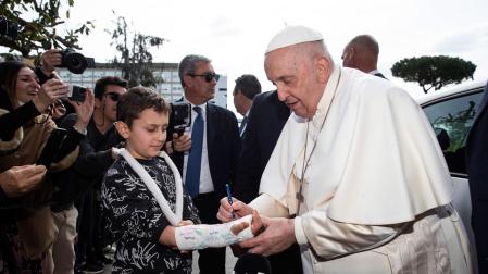 El papa Francisco firma un autógrafo en la escayola de un niño que lo esperaba a su salida del hospital, este sábado