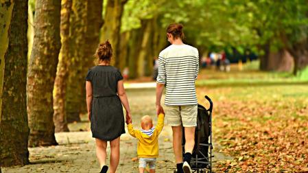 Imagen de archivo de dos padres junto a su hijo de paseo