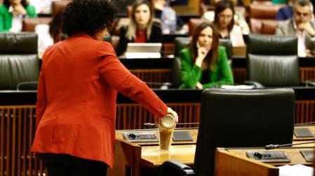 La diputada del Grupo Mixto Maribel Mora derrama arena en el escaño del presidente de la Junta, Juanma Moreno, durante el pleno del Parlamento andaluz donde se debate una proposición de ley del PP y Vox para reordenar los regadíos de la Corona Norte de Doñana
