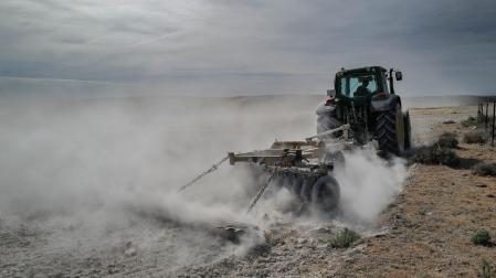 Un tractor ara la tierra seca en un campo de Belchite