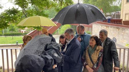 El candidato de Geroa Bai a la Alcaldía de Pamplona, Koldo Martínez, bajo los paraguas en un acto electoral este domingo junto a la pasarela de Labrit de Pamplona