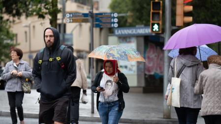 Varias personas con paraguas pasean por una de las calles de Barcelona bajo la lluvia