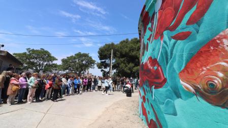 Asistentes a las visitas guiadas a las obras de la tercera edición del festival contemplan uno de los murales.