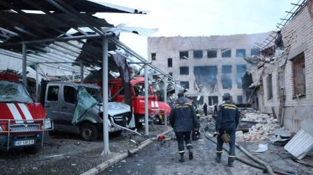 Personal de rescate camina junto a los vehículos destruidos en un complejo de bomberos del Servicio Estatal de Emergencia gravemente dañado por un ataque con misiles rusos, en Dnipro